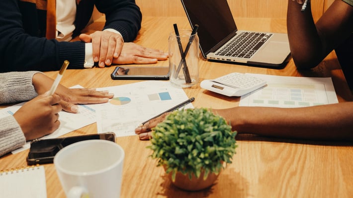 Table avec des mains travaillant sur des documents papier et un ordinateur - ©Pexels Kindelmedia